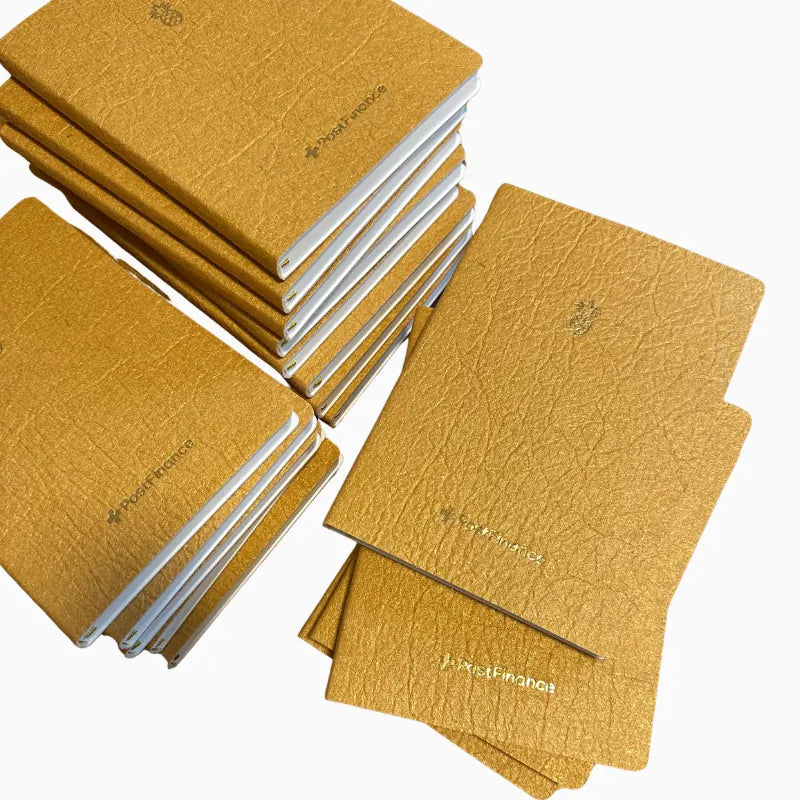 Individuelles Notizbuch für PostFinance mit goldener Logoprägung